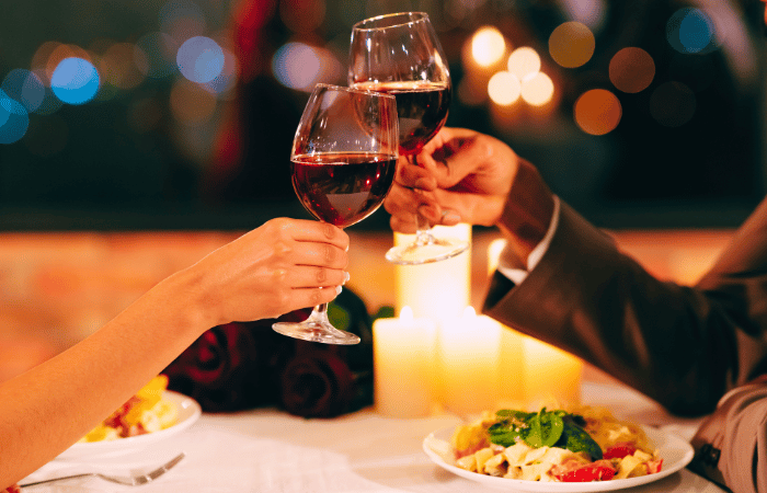 ワイングラスで乾杯する男女の手元とキャンドルのあるディナーシーン